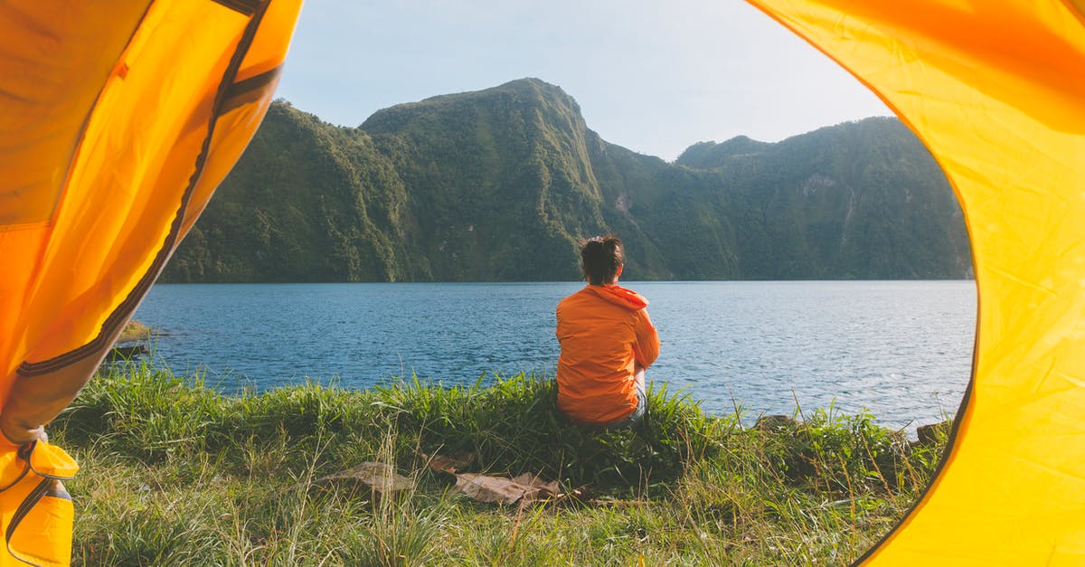 Annapurna Tilicho Lake without camping? - Person Sitting on Grass Field Facing on Body of Water