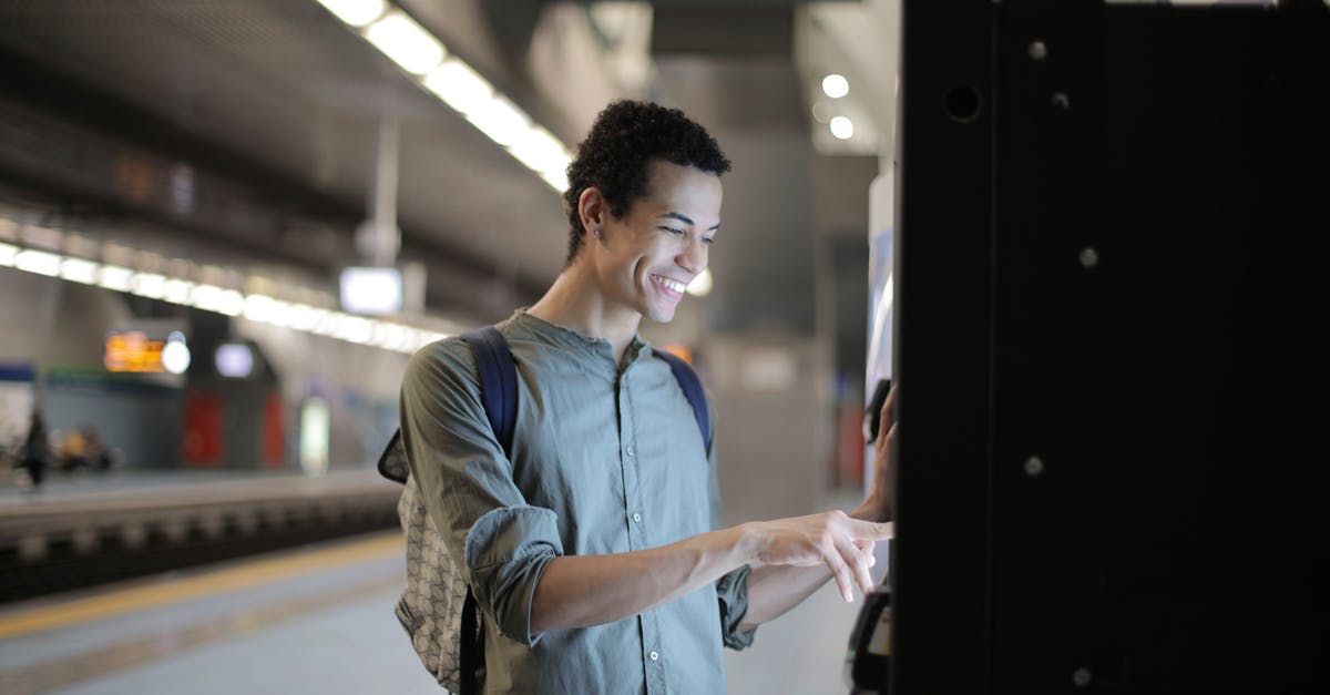 Any Maestro ATM in the US? - Joyful young African American male in casual clothes with backpack focusing and interacting with vending machine at underground station against blurred railway platform