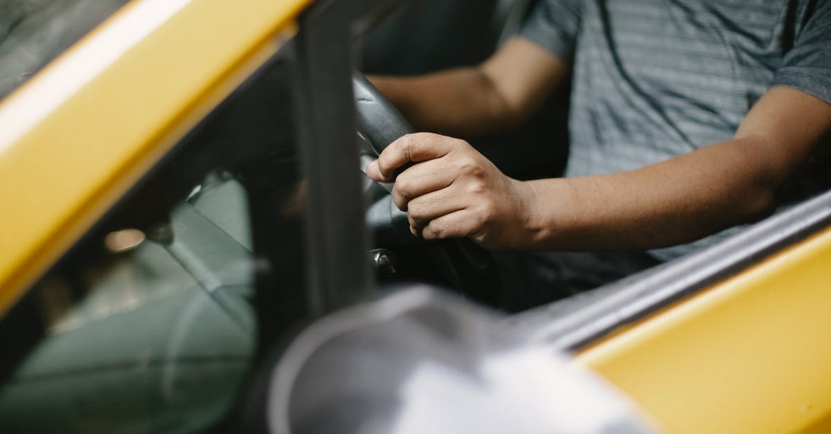 Any ride-sharing services for getting from Indiana to Texas? - From above of crop unrecognizable male in polo shirt driving yellow cab on city street in daytime