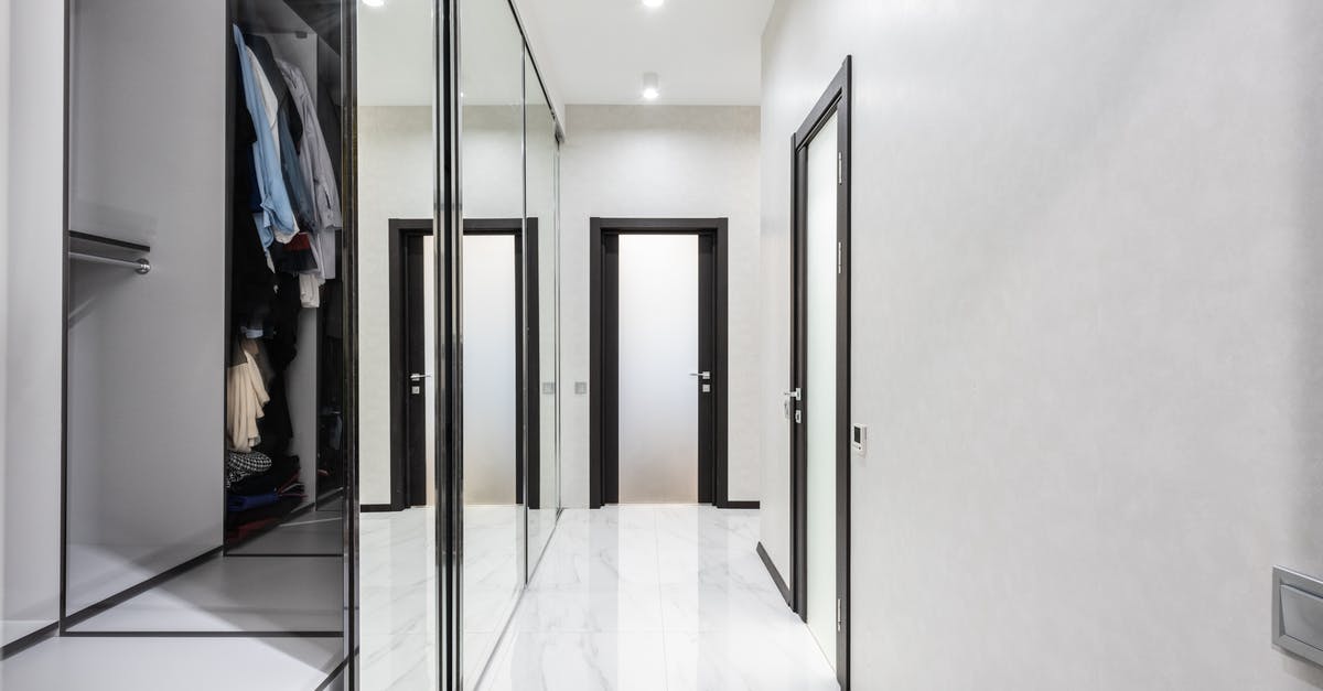 Apartment in Berlin for long stay (Two months) [duplicate] - Long light corridor with white walls and opened wardrobe with cloth in modern apartment with closed doors and glowing lamps