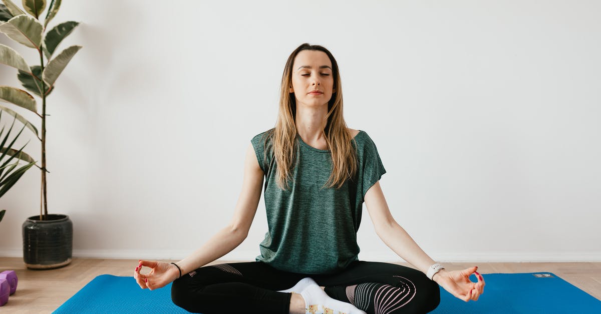 Apartment in Munich [closed] - Serene blond lady in sportswear sitting with crossed legs and closed eyes while practicing yoga at home near potted plants