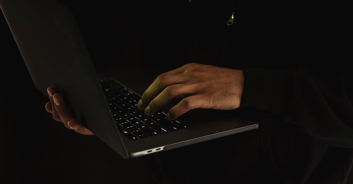 App or website showing cheap business class flights? - Crop unrecognizable man using laptop in darkness