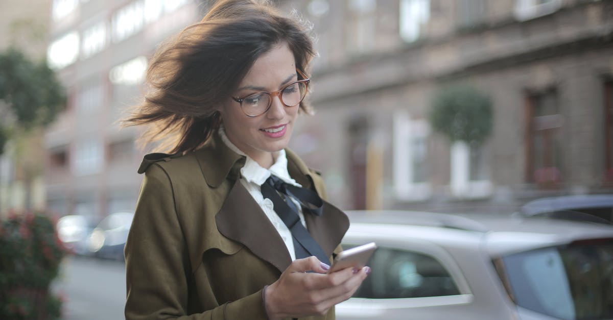 App where one can specify transit city - Stylish adult female using smartphone on street