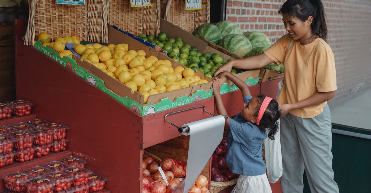 Apple Store in Ankara or Turkey - Small ethnic girl taking fruits from box with mother