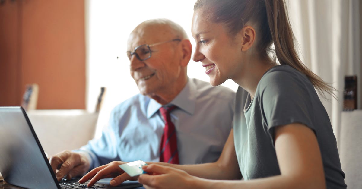 Application for schengen visa. Proof of financial support - Young woman in casual clothes helping senior man in formal shirt with paying credit card in Internet using laptop while sitting at table