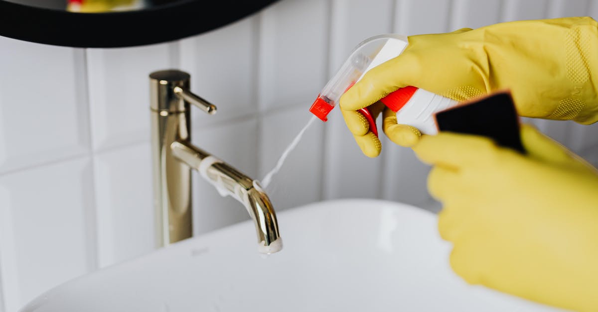 Apply for F1 from home country after B1 extension - From above anonymous housekeeper in yellow rubber gloves spraying cleaner to chrome water faucet in bathroom