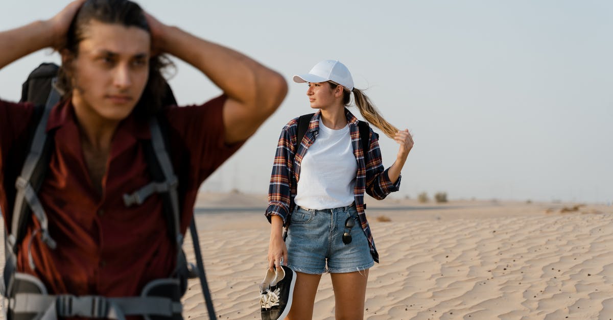 Applying for a Schengen visa as a tourist in Romania? - Woman in Blue Denim Shorts and Plaid Shirt Standing on Brown Sand