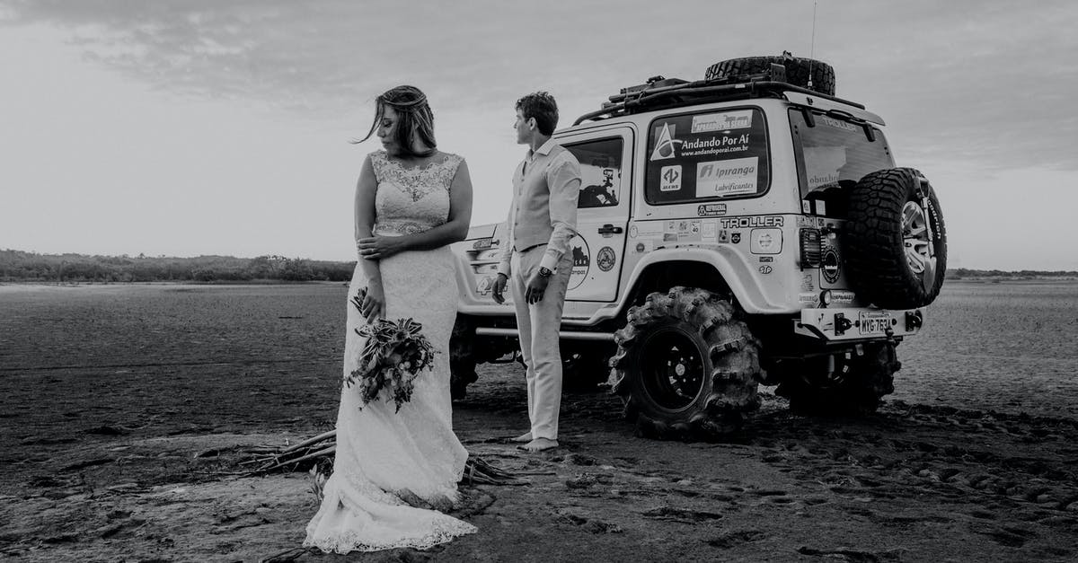 Applying for UK Visa for honeymoon trip - Groom in formal clothing and bride standing on sandy terrain