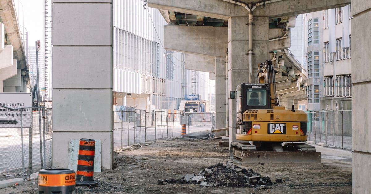 Appropiate way to safely transportate heavy laptop during flight? [duplicate] - Site of roadway under concrete bridge construction with heavy equipment on dirty ground