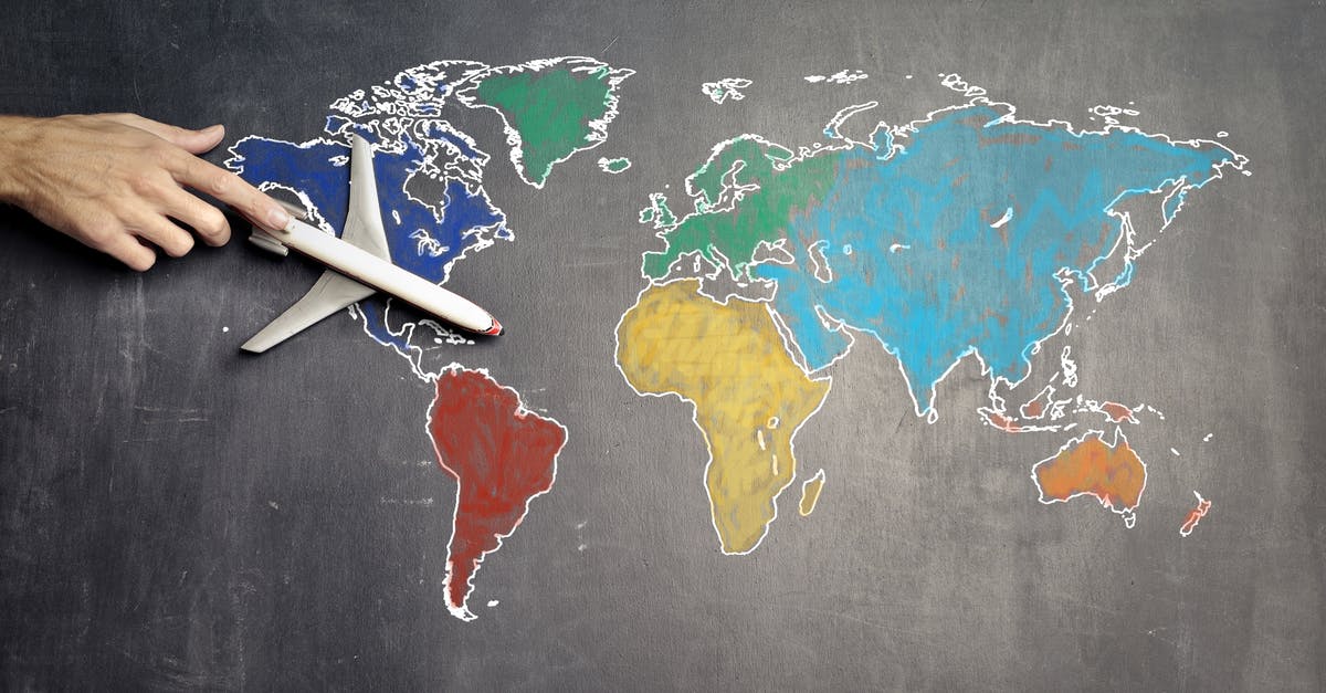 Are Belavia flights out of Kaliningrad considered domestic or international - Top view of crop anonymous person holding toy airplane on colorful world map drawn on chalkboard