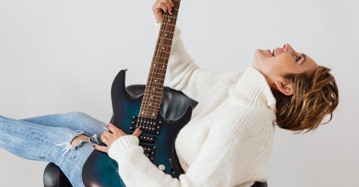 Are electric hair straighteners allowed on flights? - Side view of cheerful short haired female in casual clothes laughing while playing electric guitar in comfortable armchair against white background