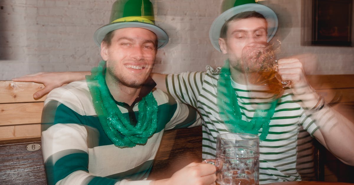 Are feathers in my hat allowed through UK & Irish customs? - Through glass wall view of smiling man against partner enjoying beer from jar mugs at table during Feast of Saint Patrick in bar