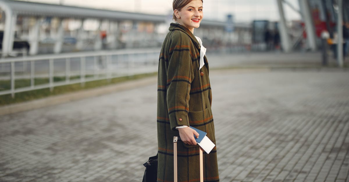 Are Global Entry LPR members obligated to carry a passport when flying into the US? - Side view of positive young woman in warm clothes smiling at camera while carrying luggage with passport walking along airport terminal