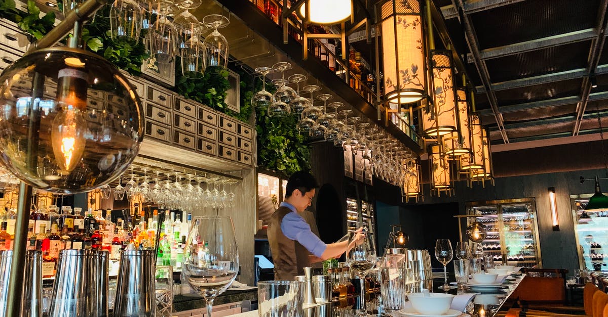 Are izakaya where the bartender doesn't stand opposite the bar inauthentic? - Side view concentrated professional barman wearing uniform working at bar counter in cozy fine dinning restaurant