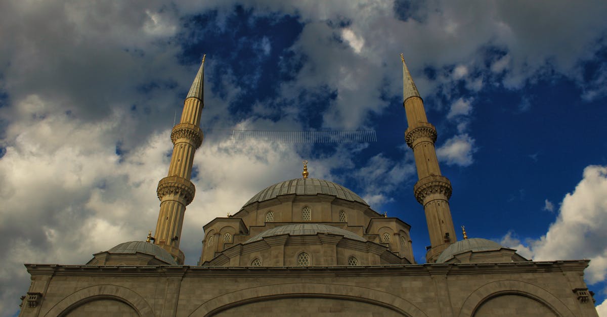 Are non-Muslims allowed to visit the Prophet's Mosque in Medina? - From below old stone mosque with dome and ornaments against cloudy blue sky on sunny day