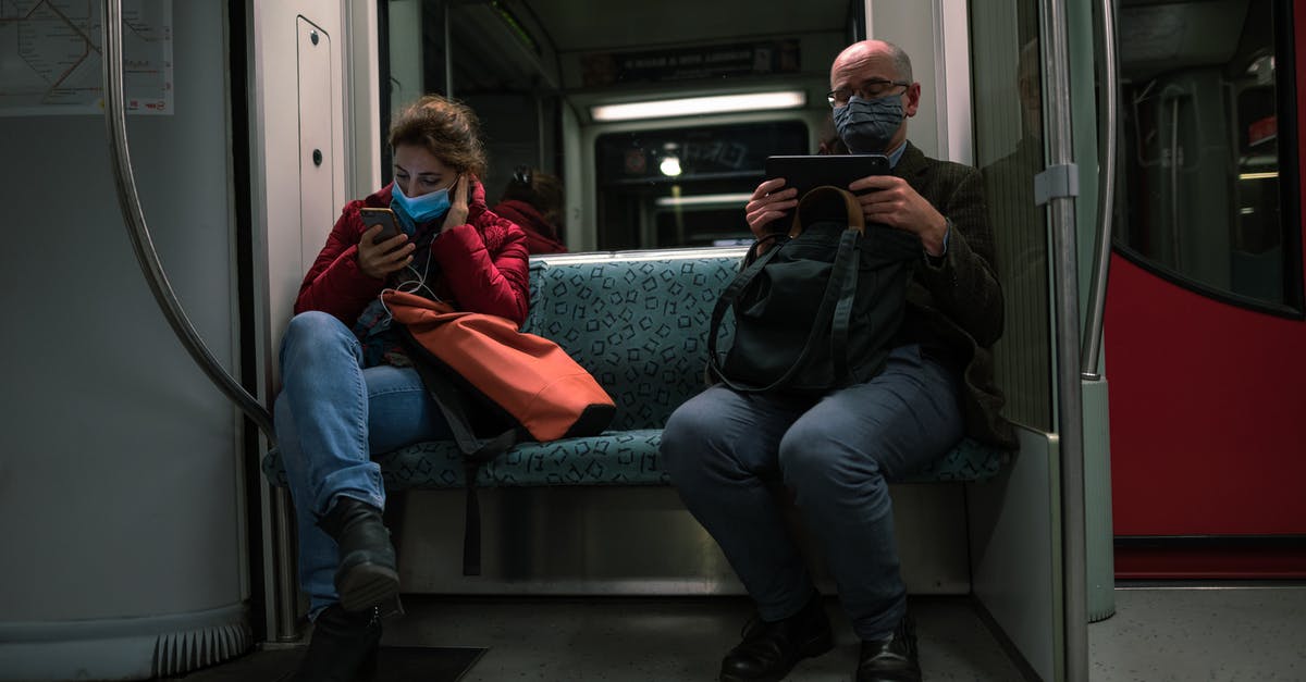 Are seat reservations still valid on delayed / overcrowded trains? - Man in Black Jacket Sitting Beside Woman in Red Jacket