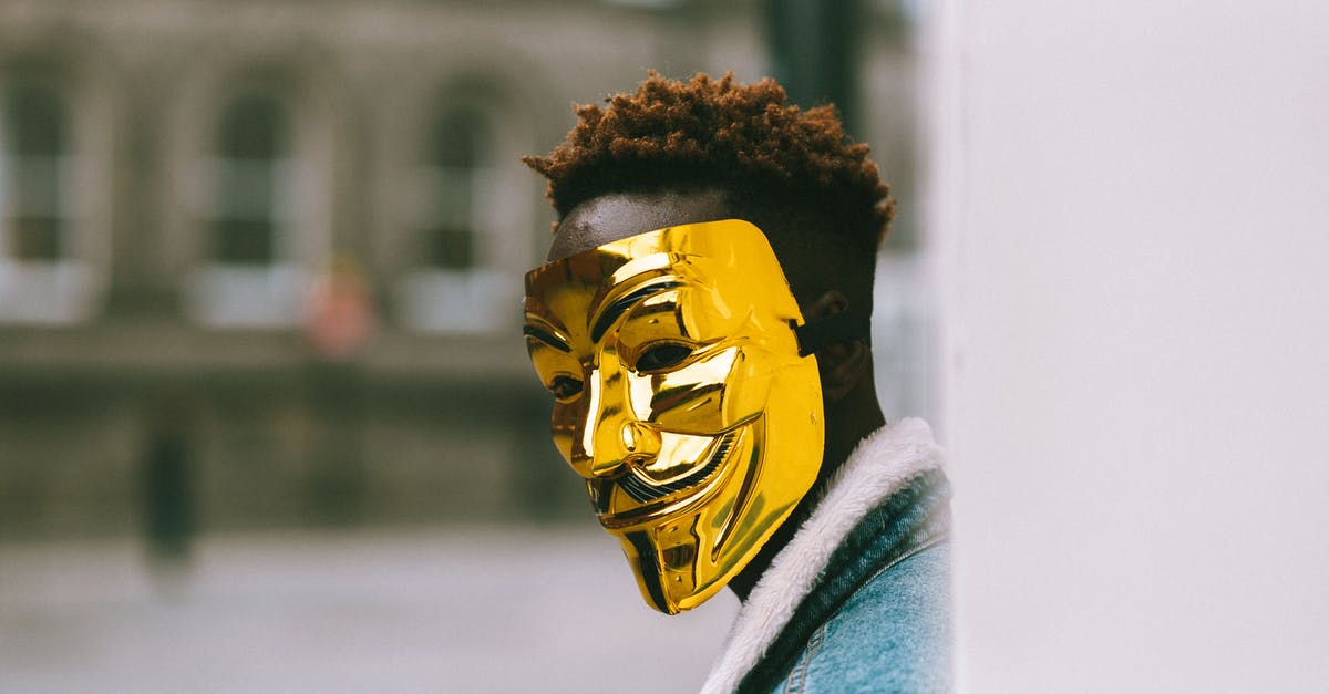 Are state boundaries a problem when using taxis in the USA? - Black activist in golden Anonymous mask standing on city street