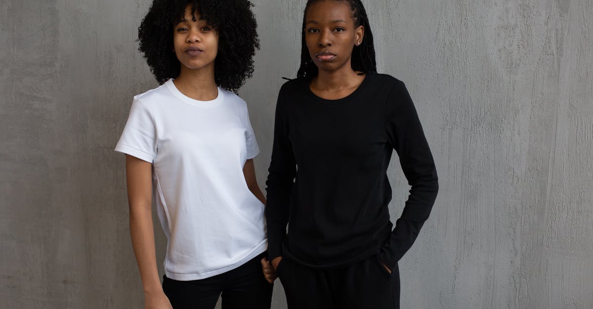 Are sweatpants frowned upon on flights? - African American female model in black sports suit standing with hand in pocket near curly haired woman in t shirt