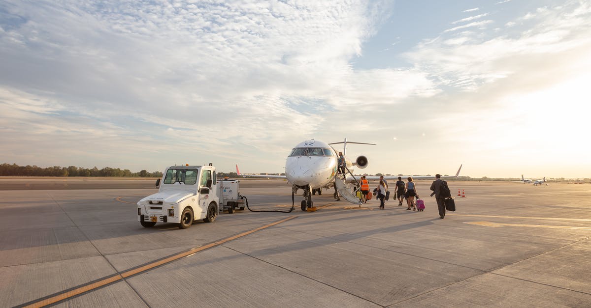 Are there any advantages to boarding a flight near the end of the boarding process? - People Walking Towards White Plane