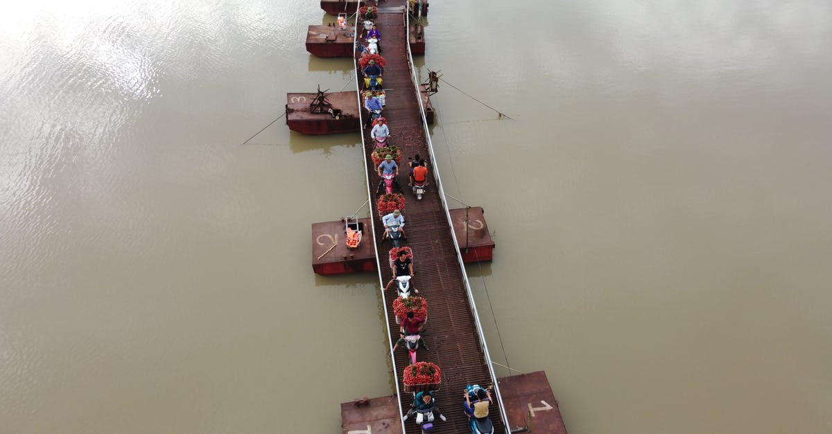 Are there any countries in South-East Asia that don't require a motorcycle licence to ride one? - People on motorbikes crossing river on floating bridge