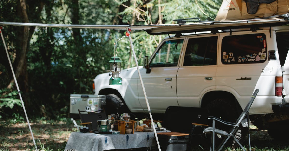 Are there any free camper parks in Australia? - Camper offroader with roof top tent and awning camping in nature among green trees in sunny day