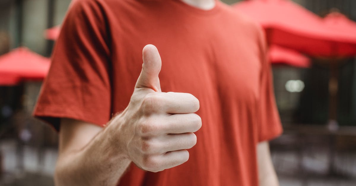 Are there any good Uber-like taxi apps in Bulgaria? - Crop anonymous young male in red t shirt showing thumb up gesture while standing on city street on sunny day