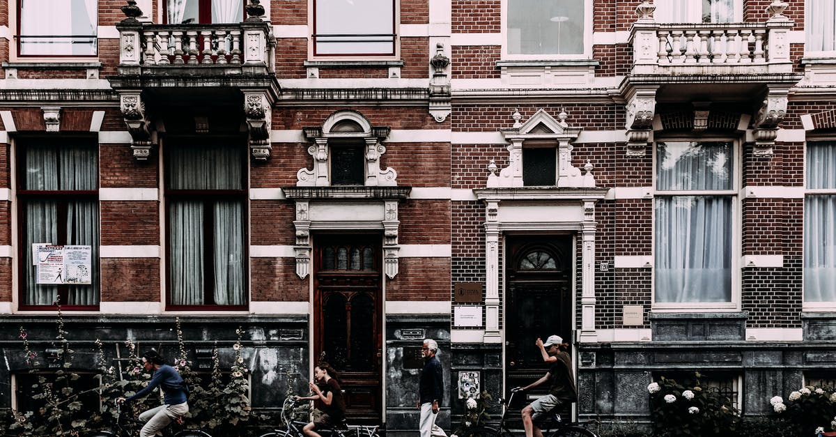 Are there any InterContinental Hotels Group (IHG) properties in Sri Lanka? - Full body side view of cyclists on bicycles riding along aged house with brick wall doors and balconies on street