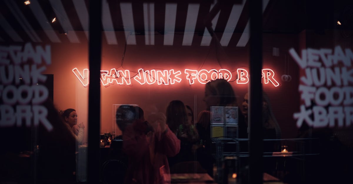 Are there any late night bars at Milano Centrale? - Through glass of group of people relaxing in modern bar with luminous signboard in late evening