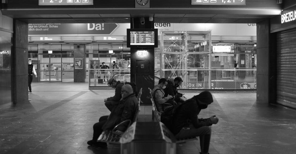 Are there any pre-check-in shops at Mumbai Airport? - People Sitting on Benches Inside an Airport