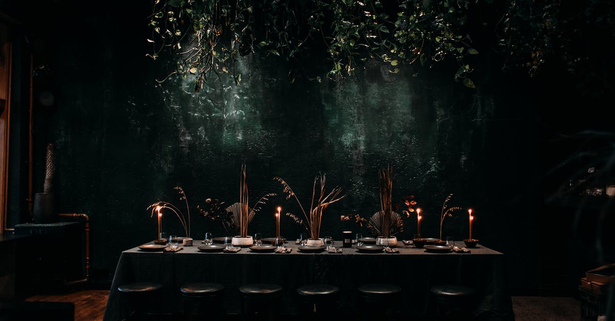 Are there any restaurants in Tokyo that serve Sannakji? - Row of stools next to long table covered with tablecloth in dark hall