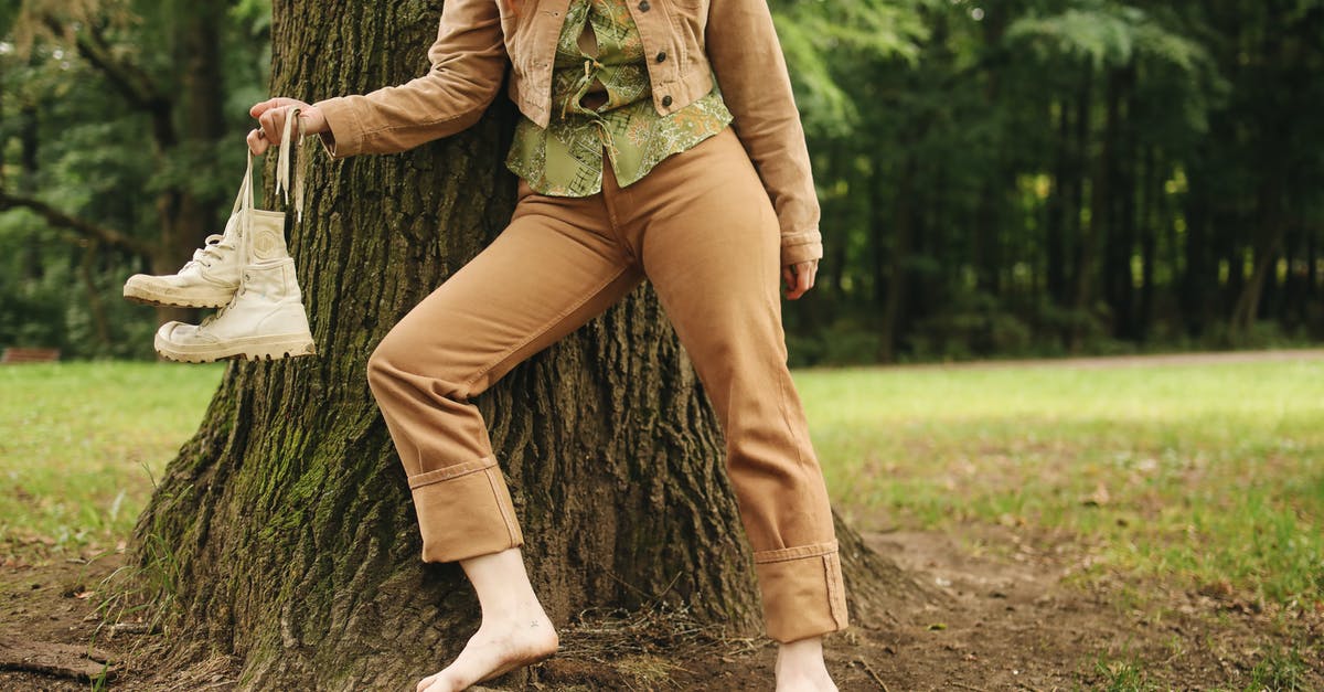 Are there any restrictions in carrying shoes in cabin baggage? - Woman in Green Jacket and Brown Pants Sitting on Tree Trunk