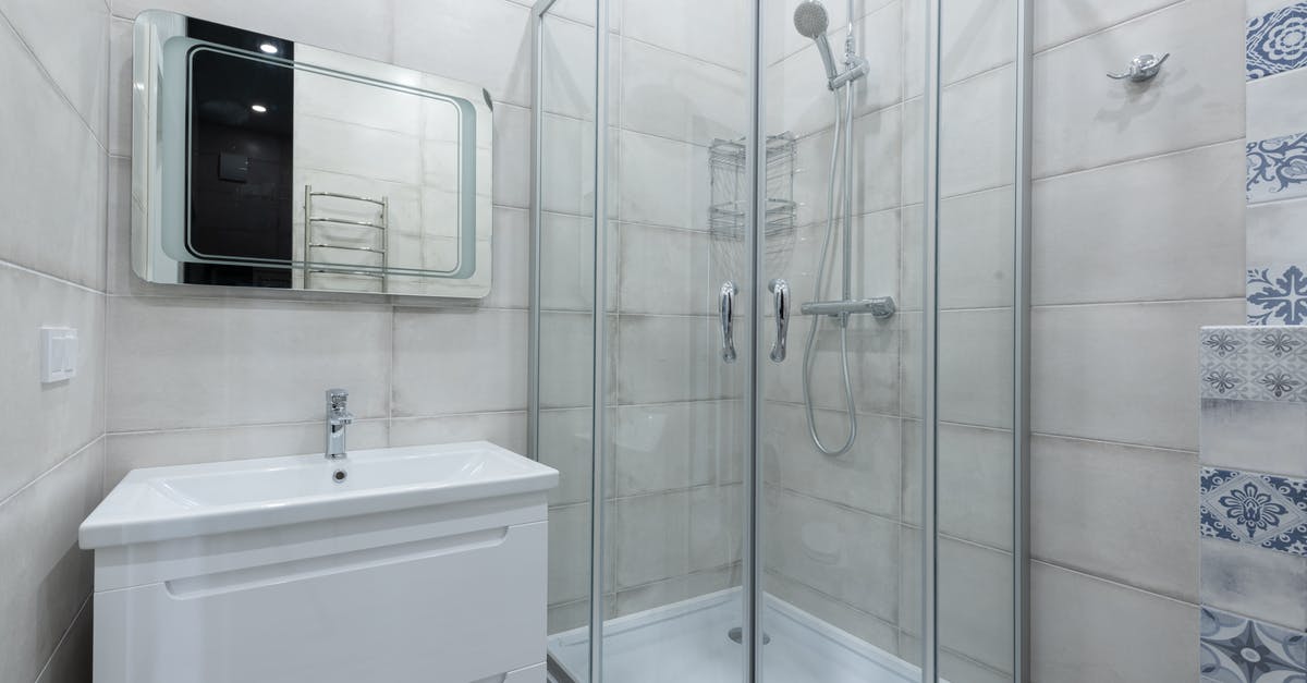 Are there any shower facilities at Heathrow Airport? - Interior of contemporary light washroom with modern glass shower cabin placed near wall with white sink and mirror at home