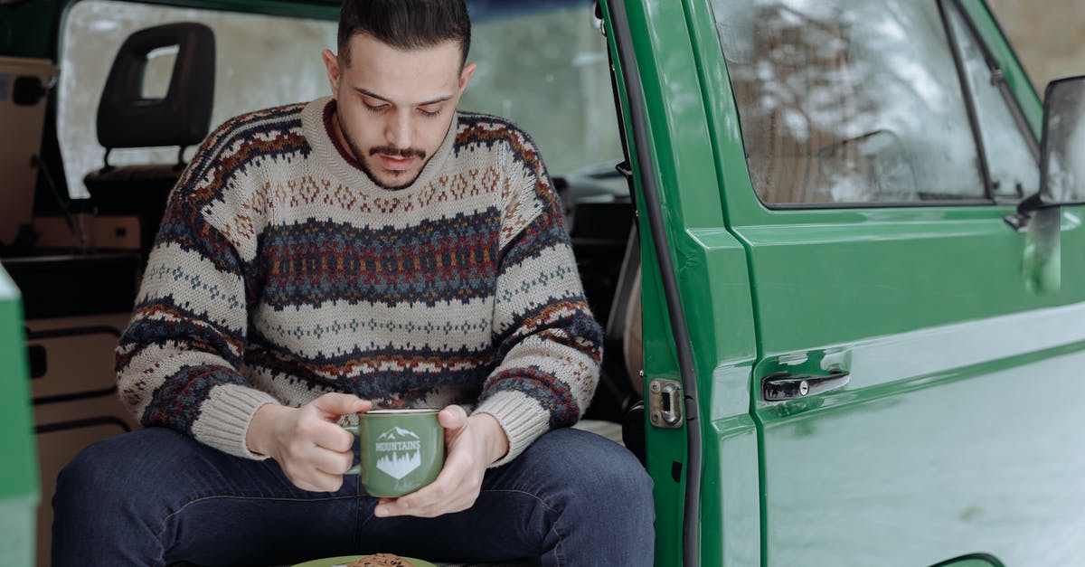 Are there any sites for camper van hire in Greece? - Woman in Brown and White Sweater and Blue Denim Jeans Sitting on Green Car