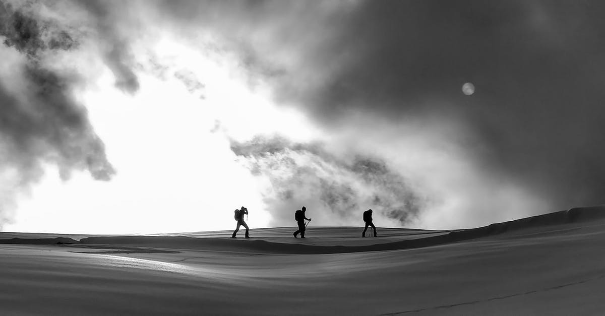 Are there area-wide ski passes in southern Poland? - Black and white silhouettes of skiers and hikers crossing spacious snowy terrain under cloudy sky on cold winter weather