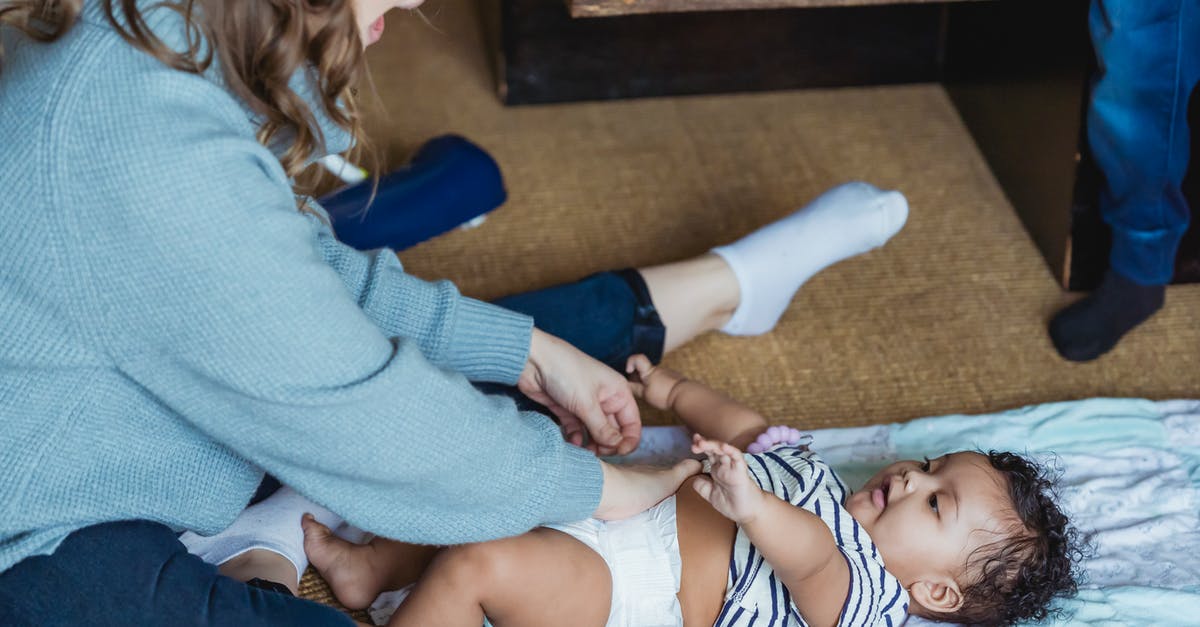 Are there baby changing rooms at Delhi airport? - From above excited young mother changing diaper and playing with adorable ethnic baby lying on linen on floor