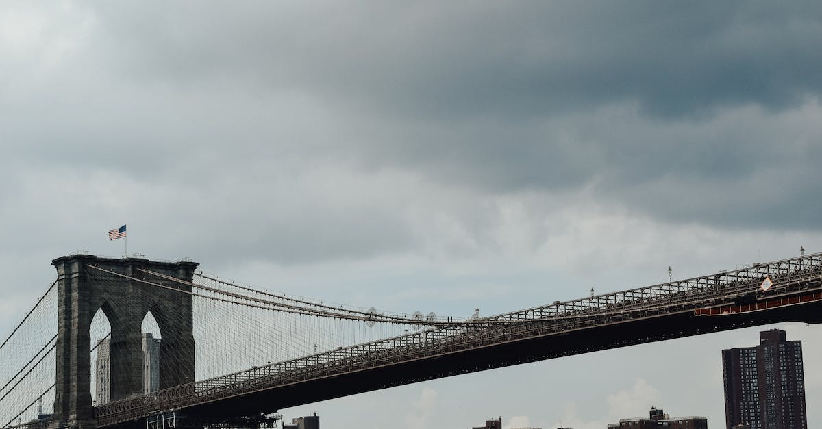 Are there countries aside from the US where I can go on storm chasing (tornado) tours? - Low angle of Brooklyn bridge with waving American flag against high rise buildings and gloomy clouds