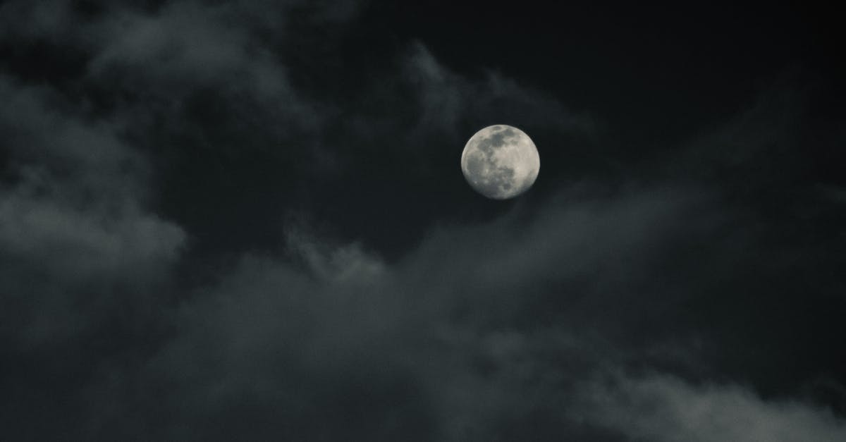 Are there good dive spots easily accessible from Kuala Lumpur, without flying? - From below of moon with craters on thick clouds floating in dark sky in evening