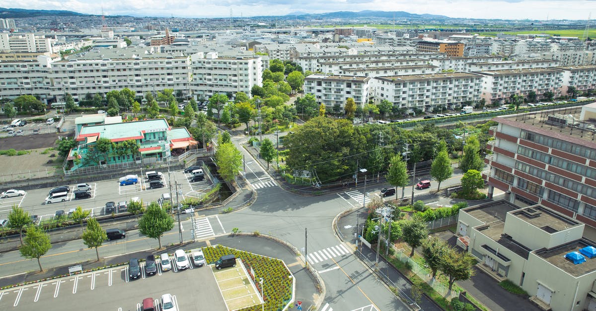 Are there hilly areas of Leuven, Belgium? - Scenery of contemporary city district with modern apartment buildings and vast parking area amidst green lush trees situated on hilly valley on sunny weather