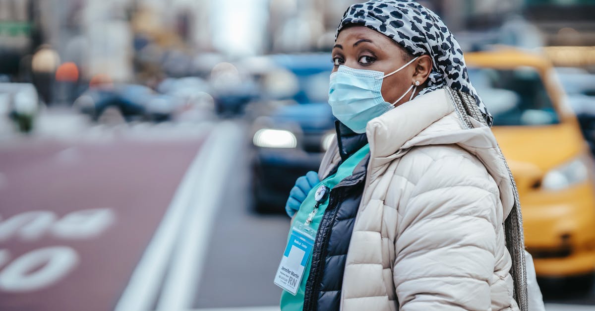 Are there limited term identification cards in the UK? - Side view of mature black female medic in outerwear with badge looking at camera on urban roadway