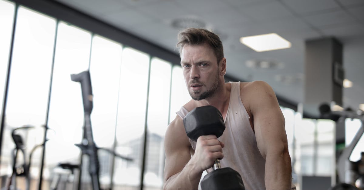 Are there metal clubs in London? - Muscular athletic man exercising with dumbbell in sports center