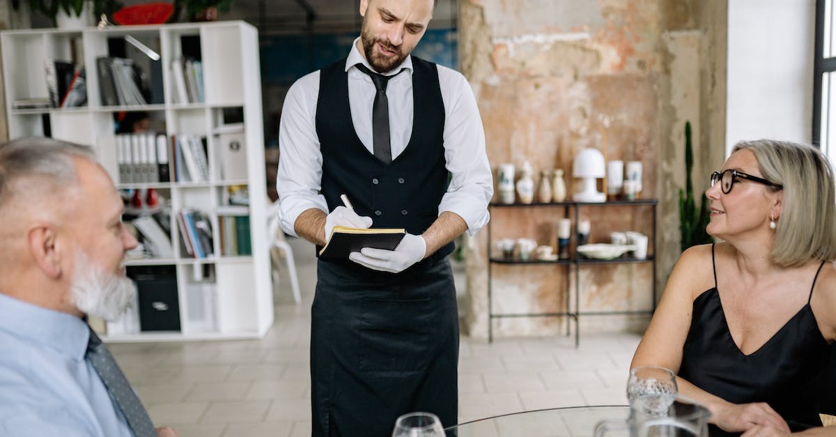 Are there restaurants or cafes with Wi-Fi in Shkodër, Albania? - Man in Black Vest and White Dress Shirt Holding White Paper