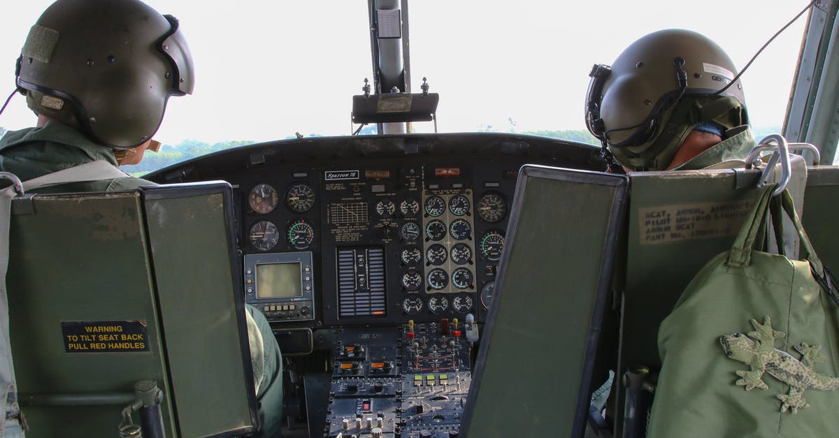 Are there scheduled flight connections operated with a helicopter? - Back view anonymous male military pilots wearing khaki uniform in cockpit and helmets flying armed helicopter