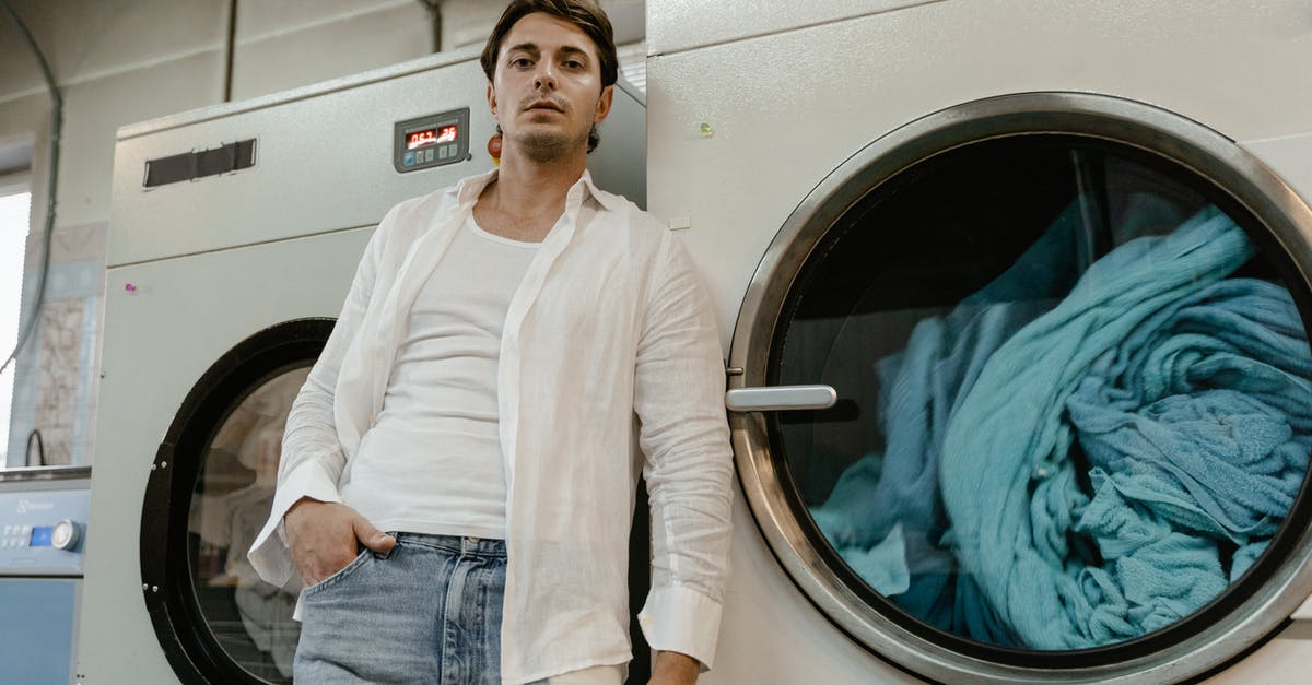 Are there self-service laundries in Arendal? - A Low Angle Shot of a Man in White Long Sleeves Leaning on a Washing Machine