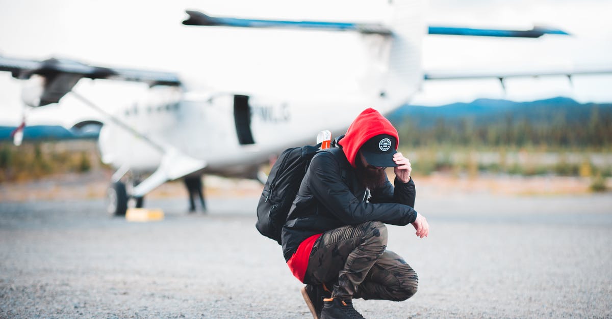 Are there tours that let you touch Stonehenge? - Full length unrecognizable male backpacker wearing casual outfit hunkering down against blurred modern light plane and touching cap peak before flight