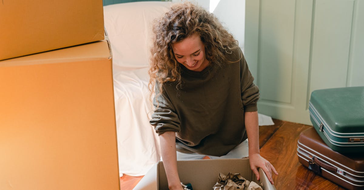 Are there websites that offer last-minute accommodation deals in Australia? - Happy woman unpacking carton box in living room