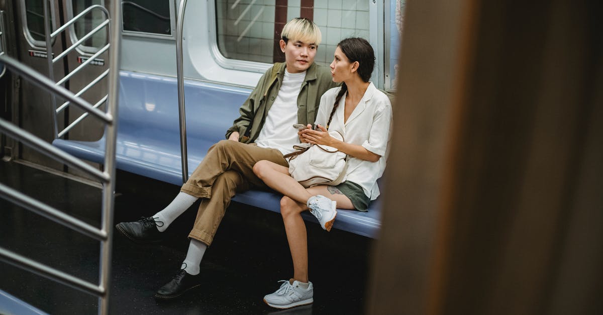 Are there wisteria tunnels close to Tokyo? - Full body of young stylish ethnic couple in casual clothes sitting in wagon while commuting by subway train