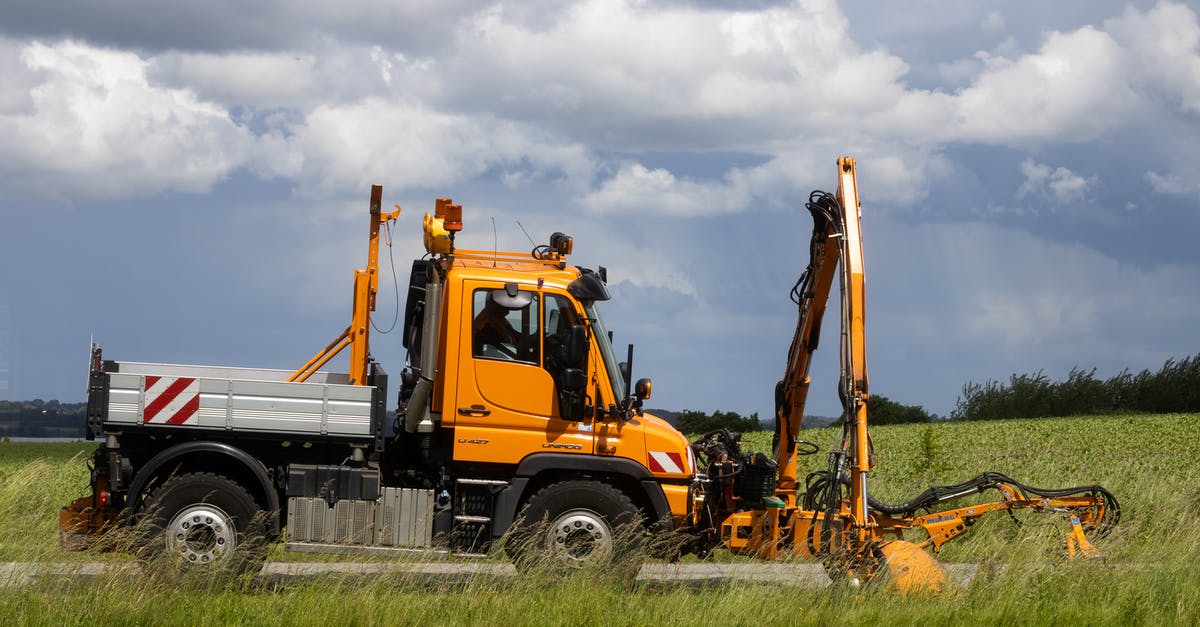 Are vignettes needed to drive on German motorways? - Orange Mercedes-Benz Unimog mowing the grass stripes next the road