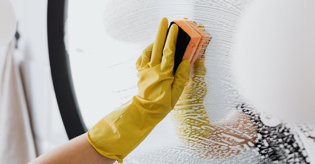 Are wet wipes subject to the TSA's 3-1-1 Liquids Rule? - Anonymous person in yellow rubber gloves using simple sponge for cleaning mirror in bathroom