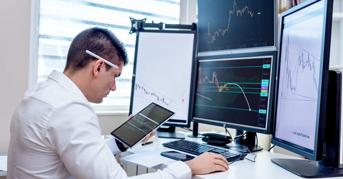 Are workstation monitors safe to pack in checked luggage? - A Man in White Long Sleeves Using a Computer with Multiple Displays