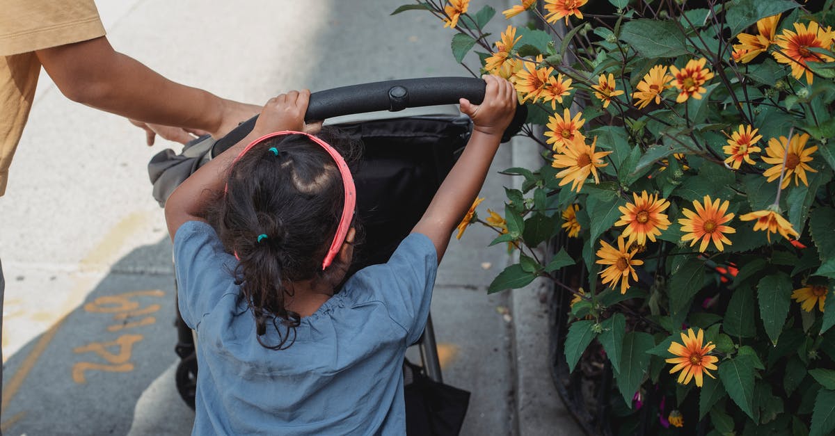 Arranging temporary childcare during a conference in an unfamiliar city - Unrecognizable ethnic girl pushing carriage